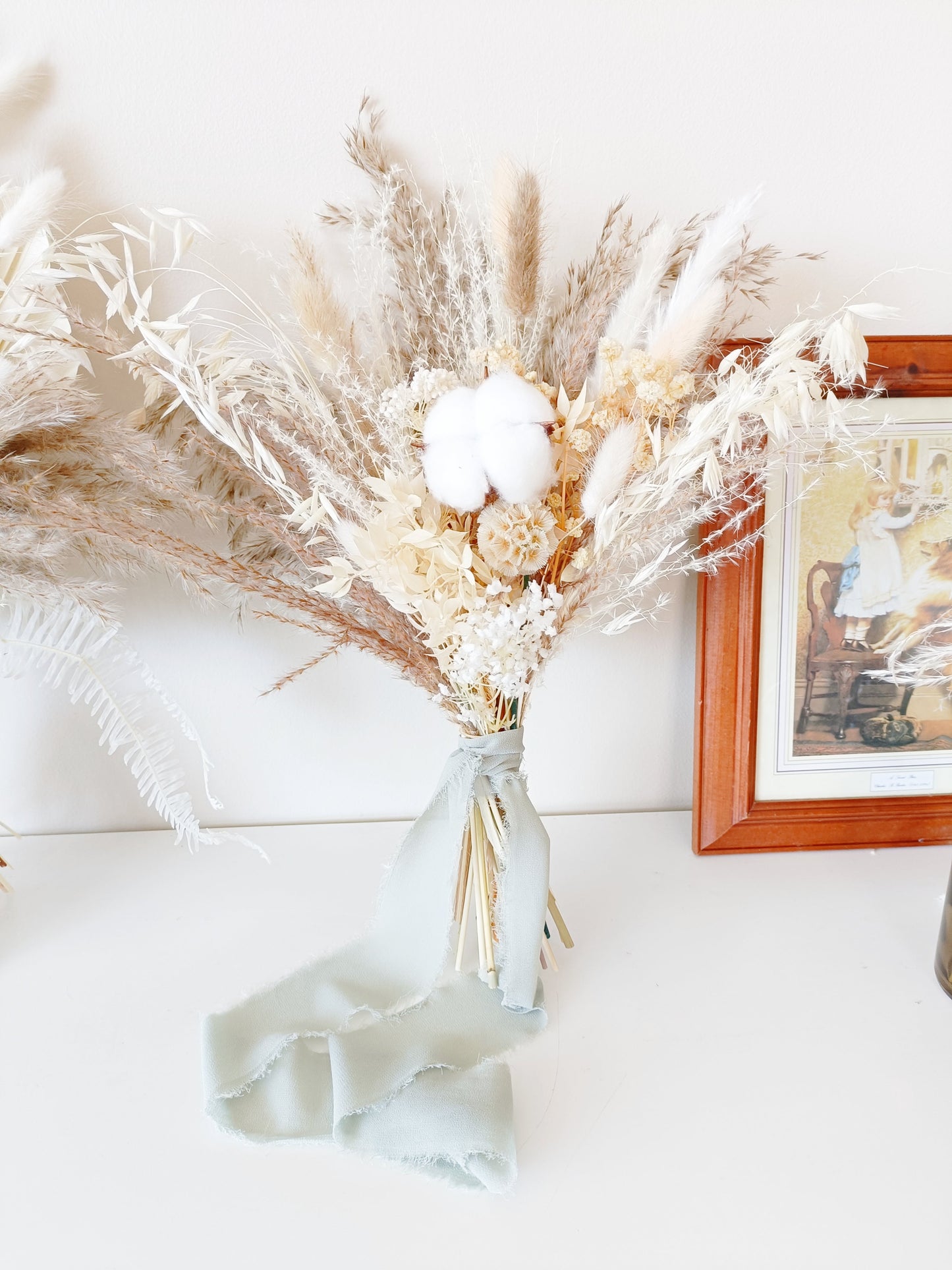 Neutral dried flower bouquet with preserved cotton, palm, pampas and ivory tones in a vase – styled for elegant rustic Australian weddings.
