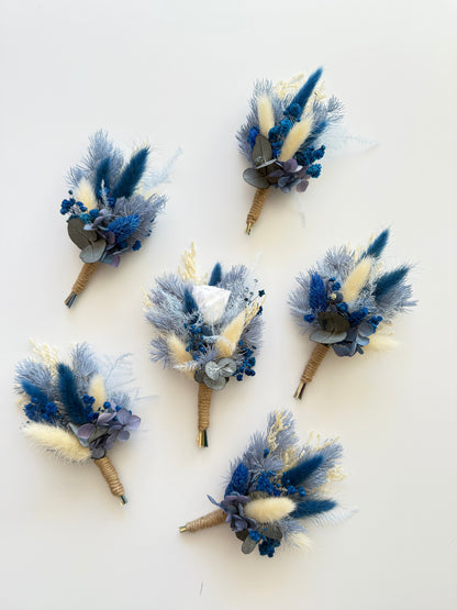 Set of three handmade blue and beige dried boutonnieres with natural jute stems, perfect for groomsmen gifts.