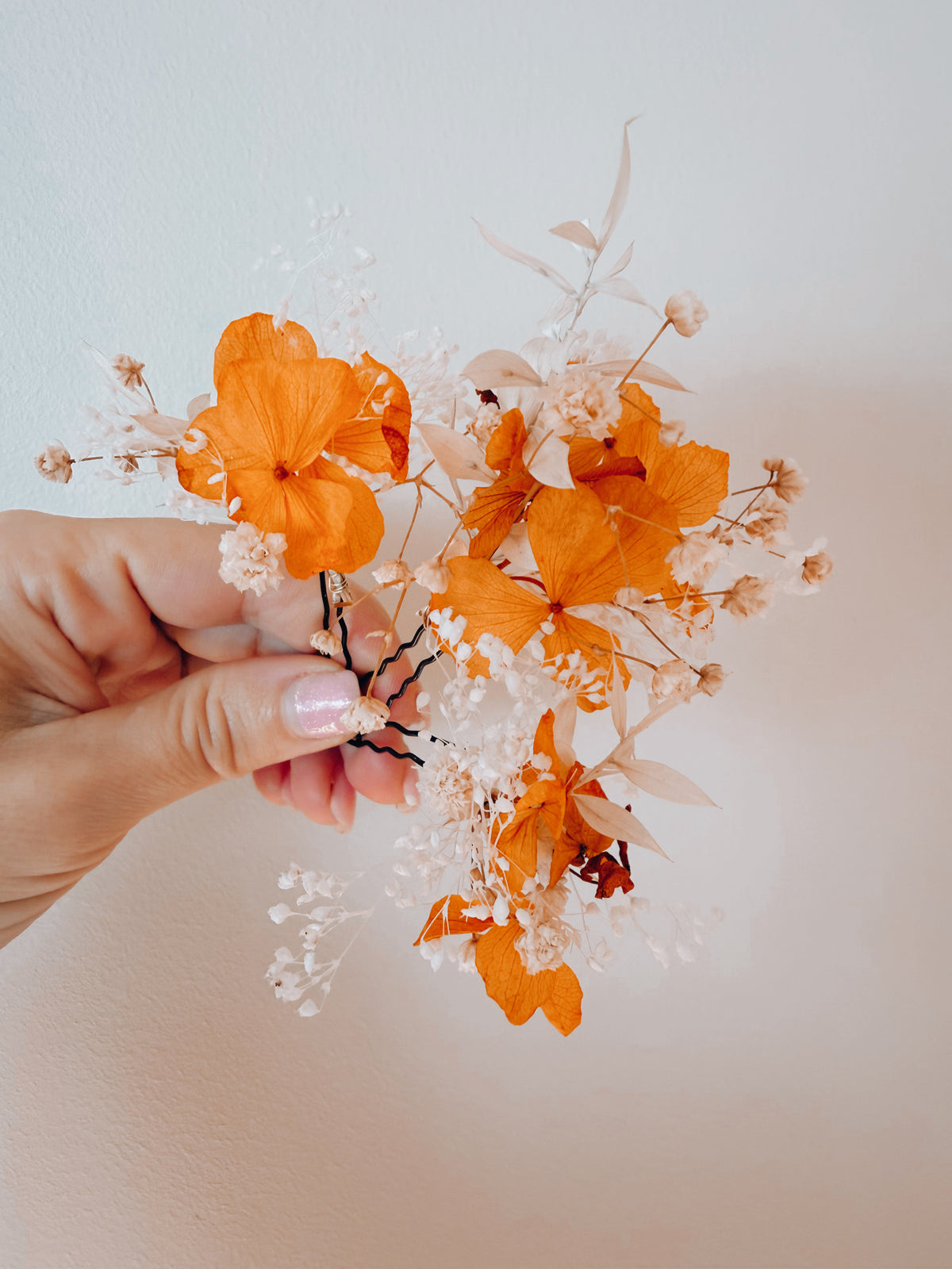 Orange and white dried flower bridal hair pins with preserved hydrangea and delicate baby’s breath for a wedding hairstyle