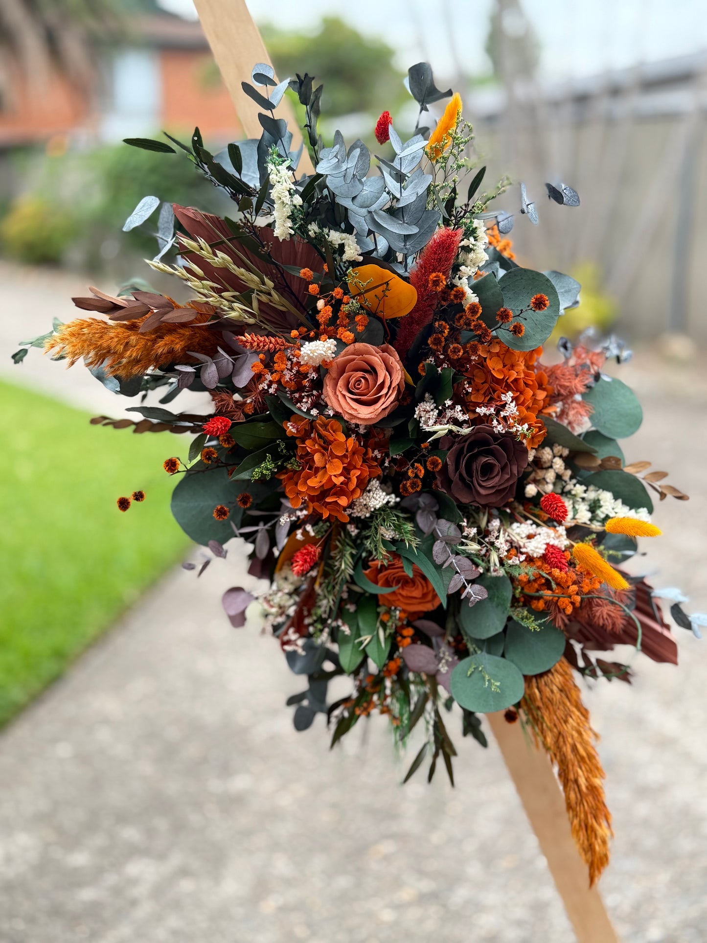 Rustic outdoor wedding arch with boho dried flower arrangements and soft draped fabric in a natural garden setting