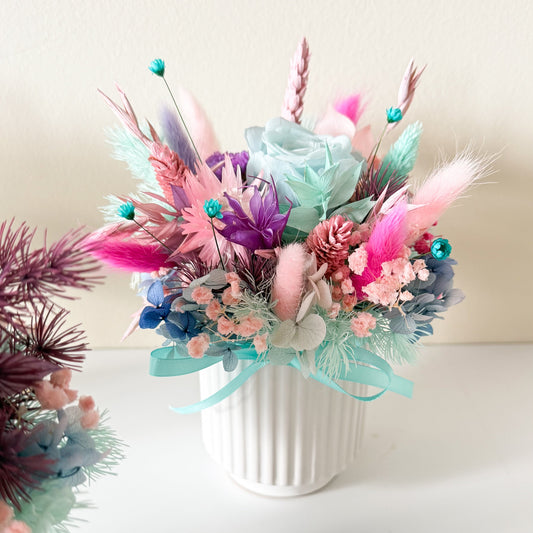 Handmade pastel dried flower bouquet with turquoise rose, pink preserved flowers in small decorative container