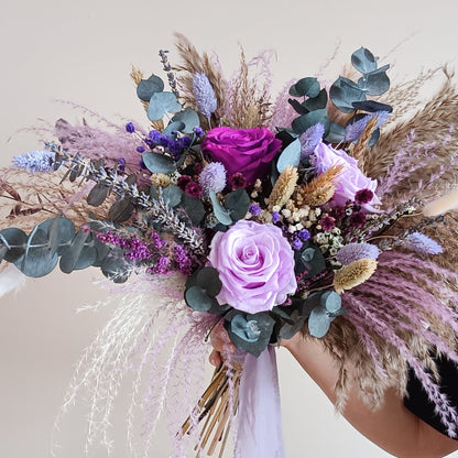 Dried flower bridal bouquet in lilac and purple tones with sola wood roses, preserved eucalyptus, lavender, and pampas grass – perfect for boho or rustic weddings. Hand-tied and wrapped with a soft ribbon.