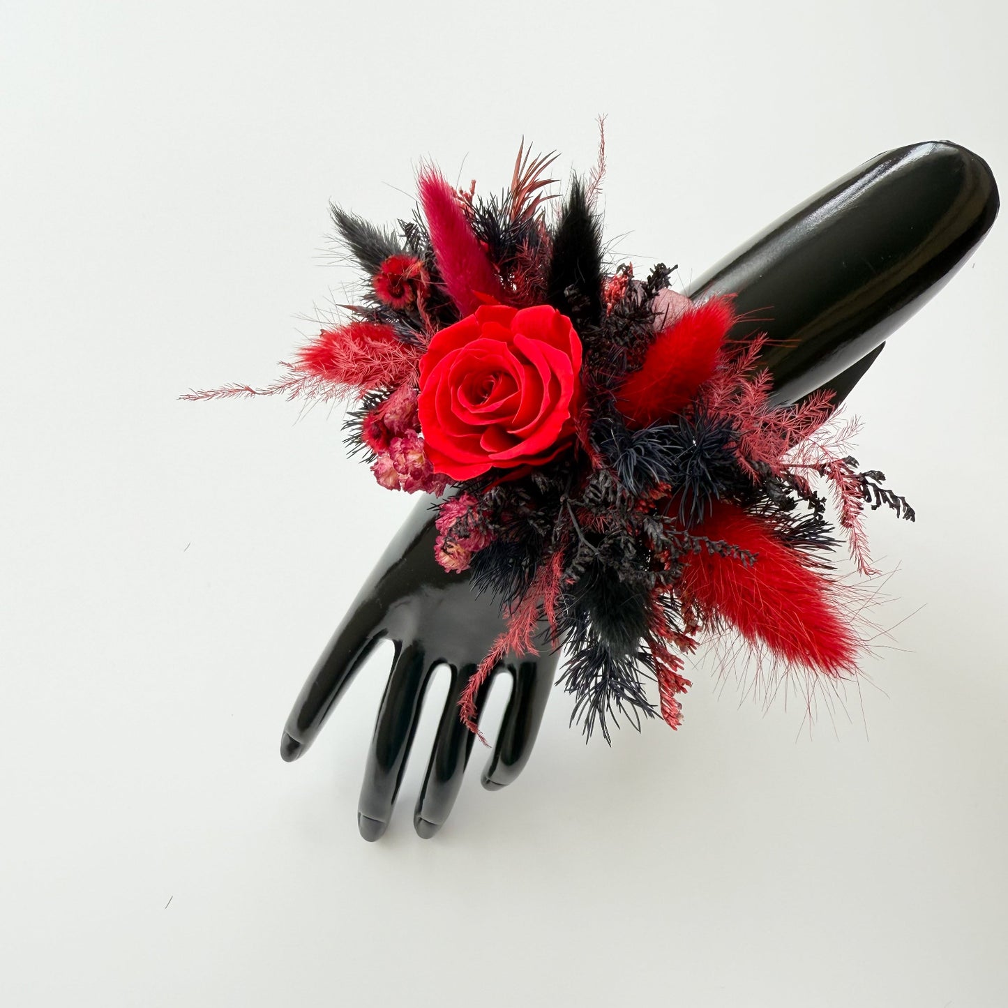 Black glove with red and black floral arrangement on a white background