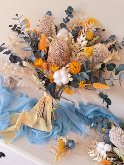 Rustic boho dried flower wedding bouquet flat lay with blue fabric and pampas grass styling