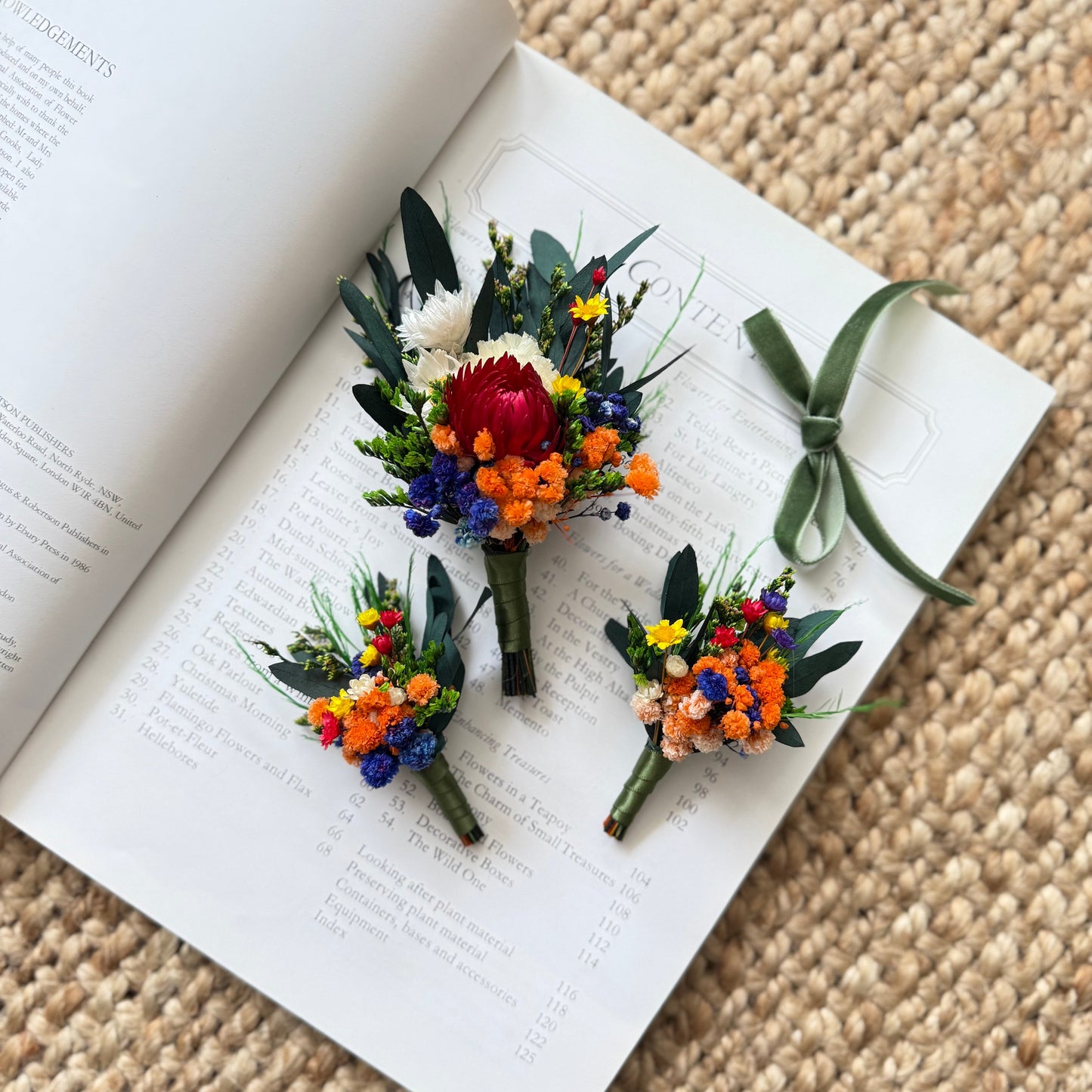 Rustic dried flower boutonniÃ¨re for groom featuring burnt orange and royal blue flowers with eucalyptus leaves