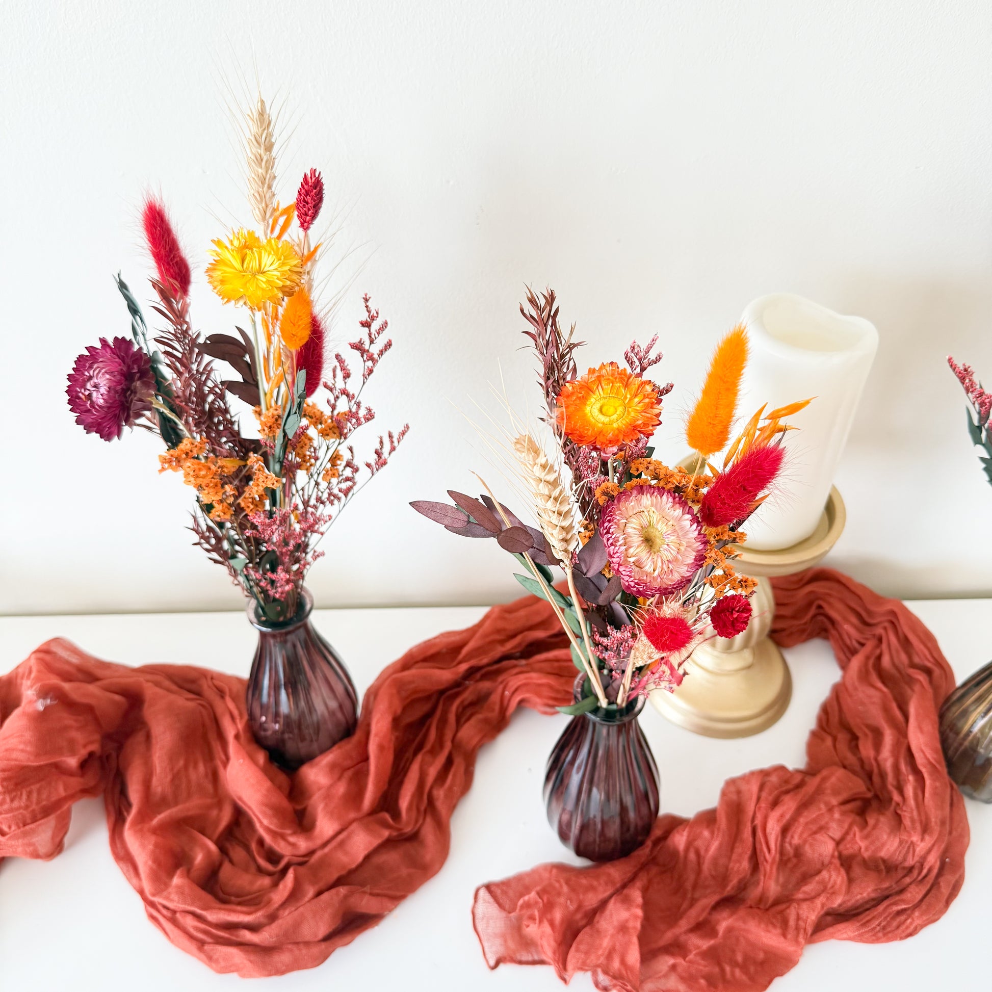 Rustic dried flower decor in orange, red, and burgundy tones with bunny tails and preserved leaves, ideal for autumn table styling.