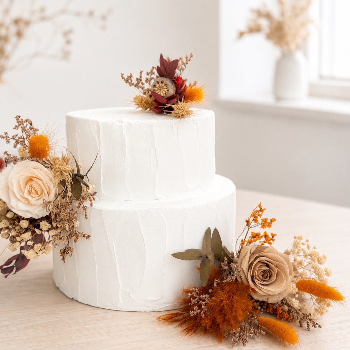 Natural dried and preserved cake topper arrangement featuring ivory roses, amber blooms and burnt orange dried foliage for a romantic boho wedding.