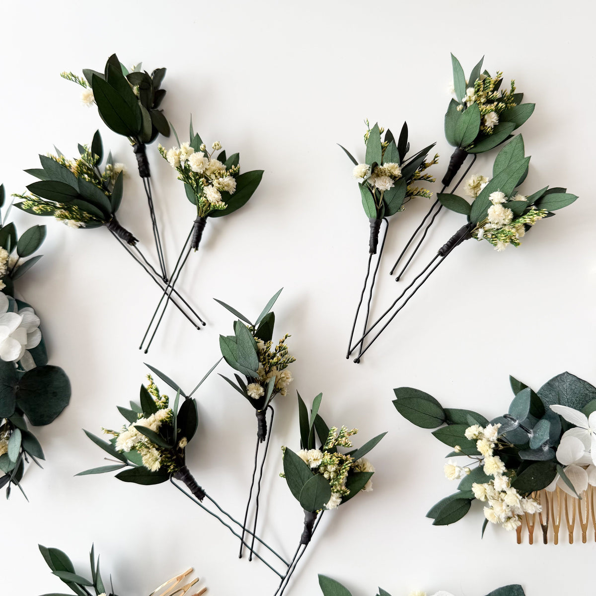 Close-up view of a floral hair pins with textured green eucalyptus and delicate white dried accents.