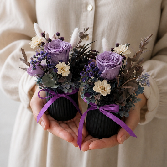 two small black pots with purple and white flowers, tied with purple ribbons.