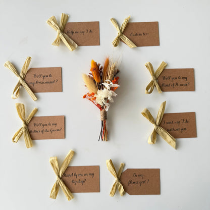 Set of wedding proposal cards with gold ribbons and a small bouquet on a white background