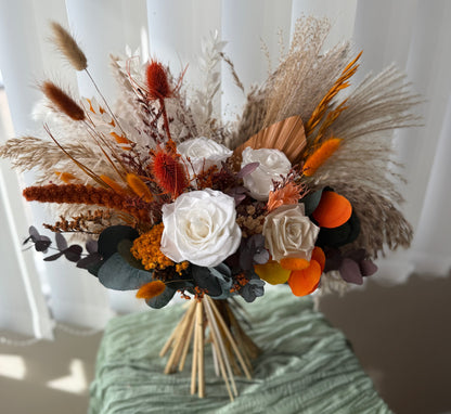 Bouquet of dried flowers and herbs on a green surface with a white curtain background