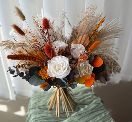 Bouquet of dried flowers and herbs on a green surface with a white curtain background