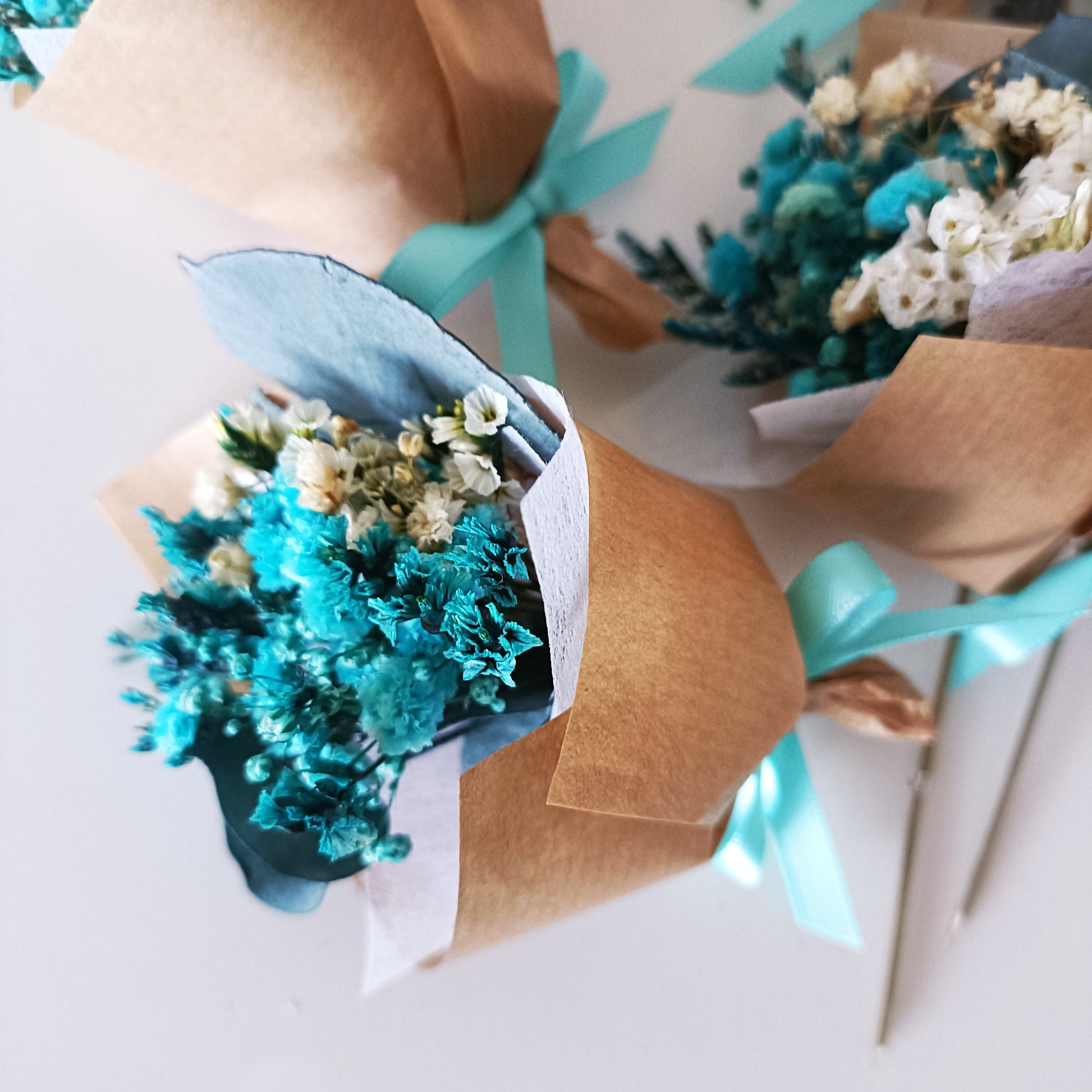 Teal and ivory dried flower arrangements tied with ribbon, great for weddings and bulk orders.

