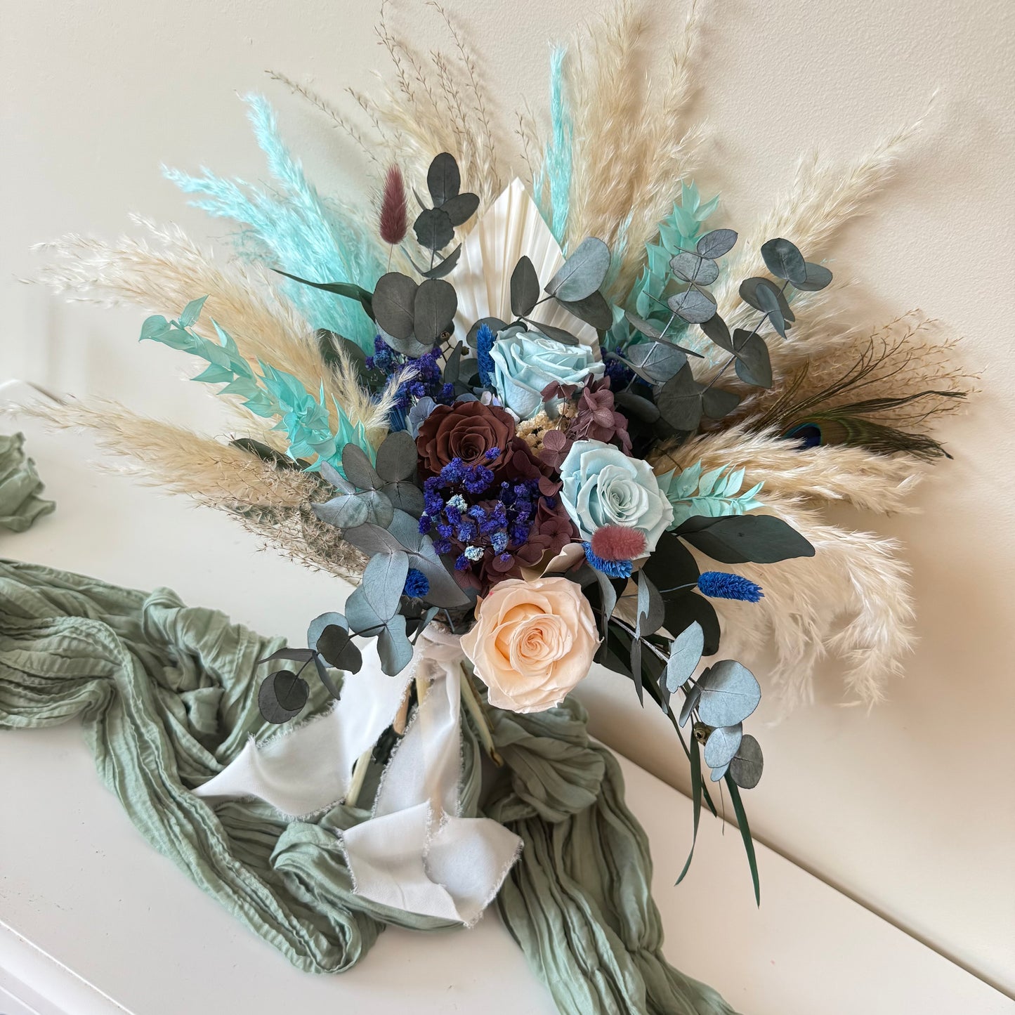 Boho ocean dried bridal bouquet with teal, navy and beige sola wood roses, preserved eucalyptus and fluffy grass.