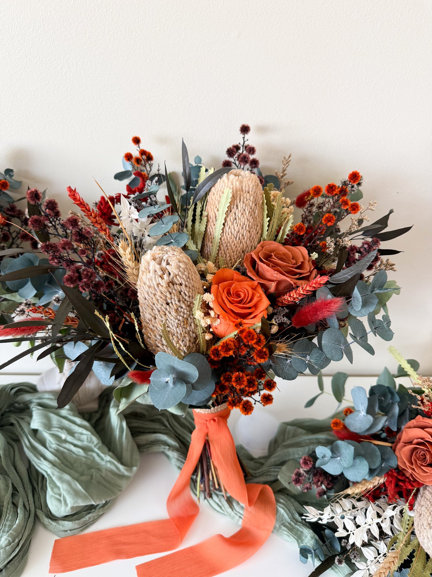 Terracotta Australian native bridal bouquet featuring preserved roses, banksia, eucalyptus and dried flowers in burnt orange, rust and blue-green tones, handmade wedding bouquet in Australia