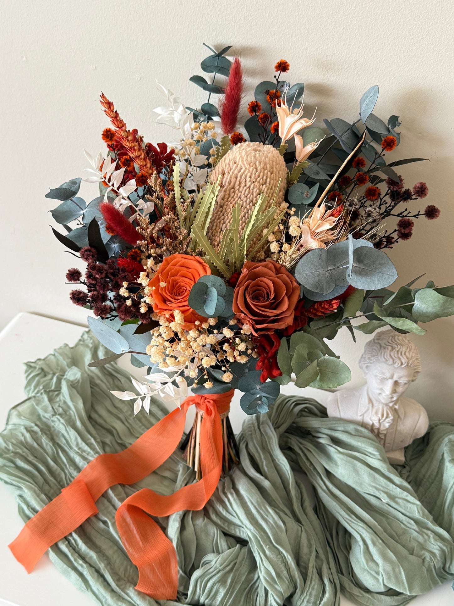 Australian native bridal bouquet with banksia, preserved roses, eucalyptus and dried flowers in terracotta, rust and sage green tones, handmade wedding bouquet in Australia