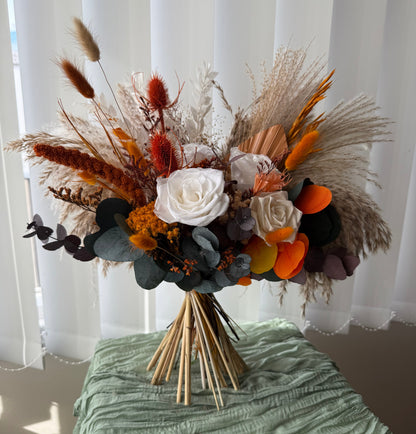 Large boho wedding bouquet with sola wood roses, pampas grass, eucalyptus, and dried florals in burnt orange, terracotta, and cream — rustic autumn bridal bouquet.
