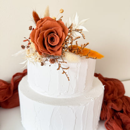 Burnt orange dried flower cake topper with sola rose, bunny tails and mustard accents on white buttercream cake