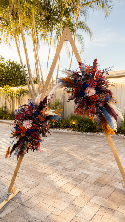 Luxury dried flower arrangements attached to a wooden triangle wedding arch