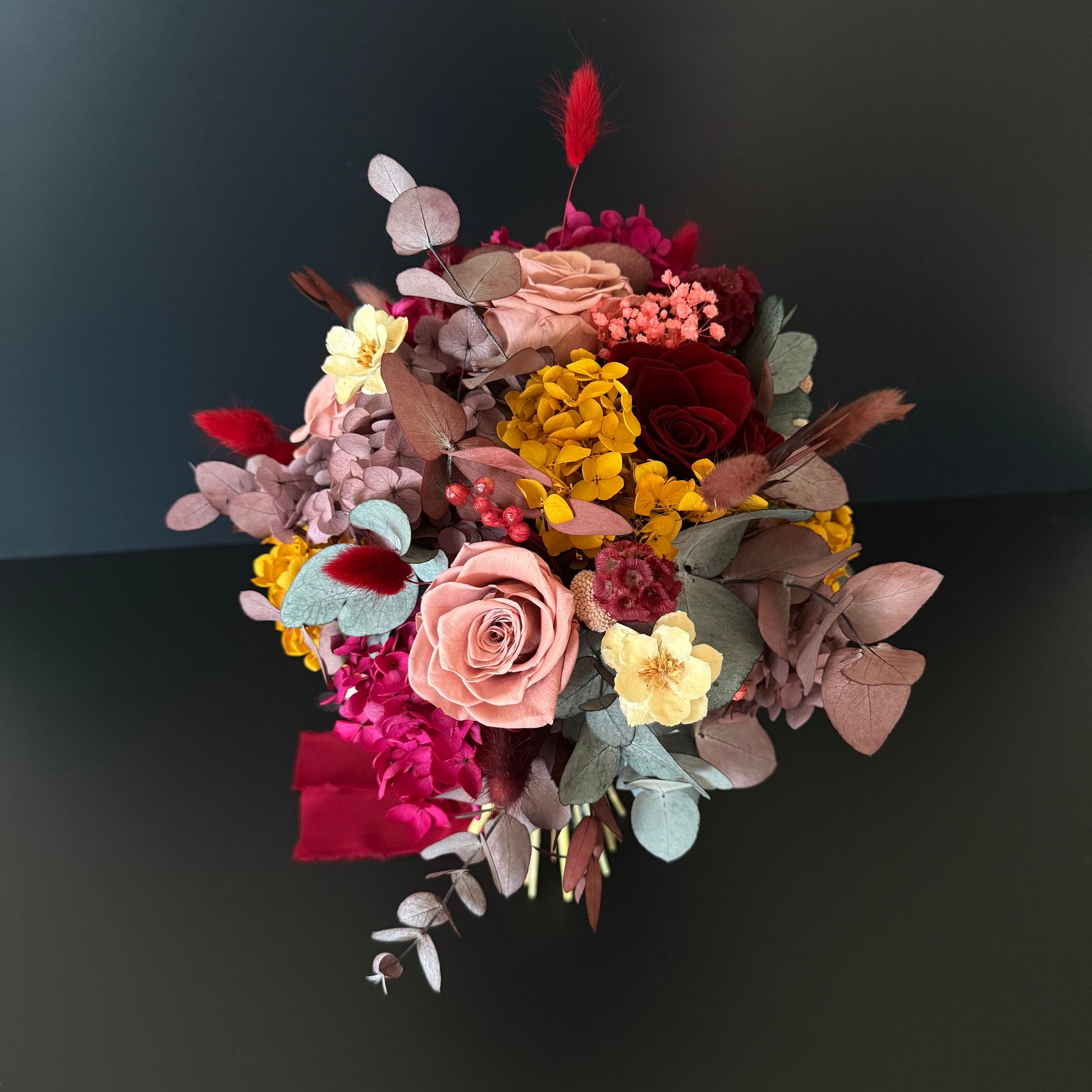 Vibrant boho dried flower bouquet in terracotta and burgundy palette, with sola wood roses and preserved eucalyptus.
