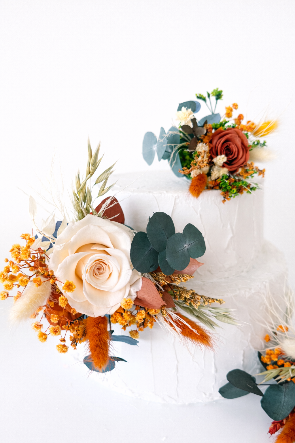 Natural dried and preserved cake topper arrangement featuring ivory roses, champagne tones and terracotta dried flowers for a romantic boho wedding.