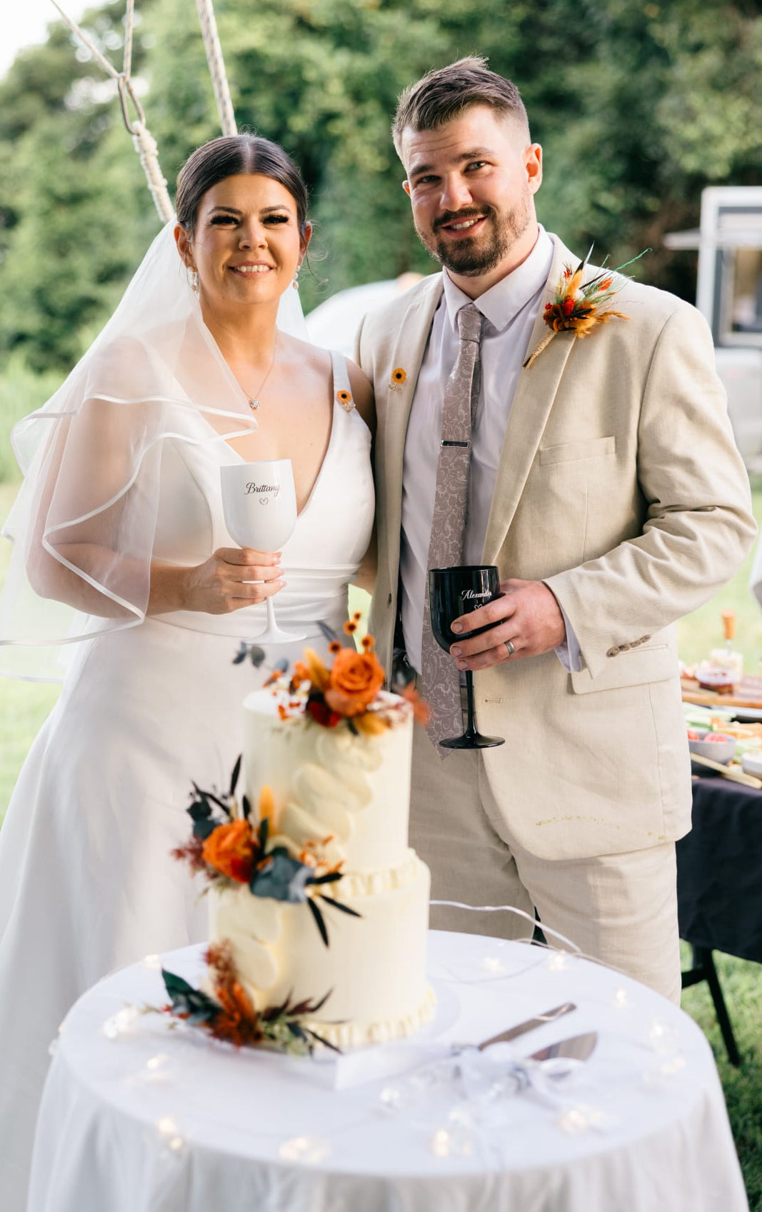 Handmade wedding cake floral decorations in terracotta rose tones, arranged with terracotta roses, warm orange blooms and dried foliage.