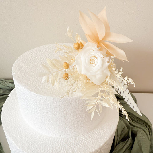 Handmade wedding cake floral decorations in ivory and white tones, arranged with ivory white roses and delicate neutral dried flowers.