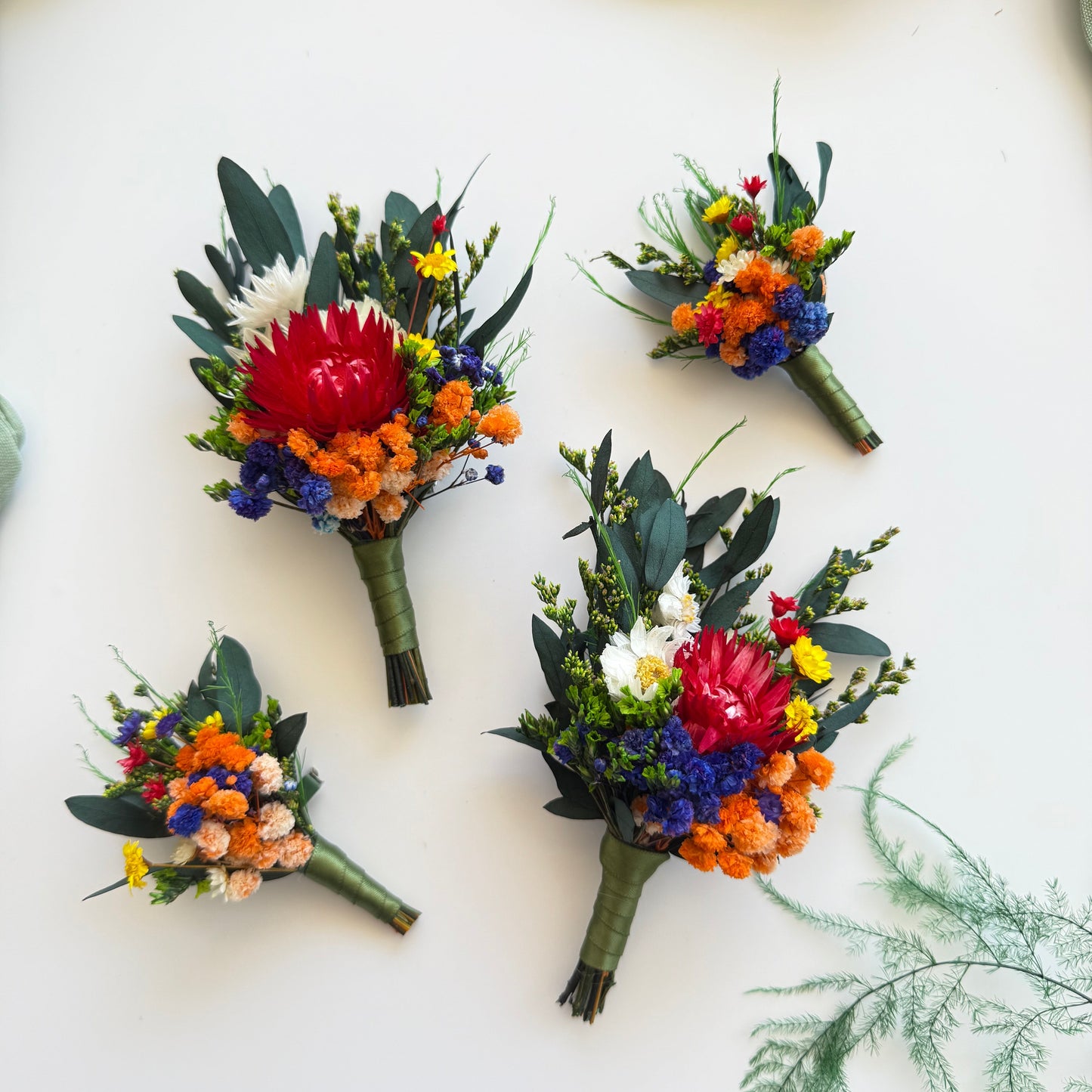 Dried flower wedding boutonniere in rustic boho style with terracotta, blue and sage flowers for groom and groomsmen