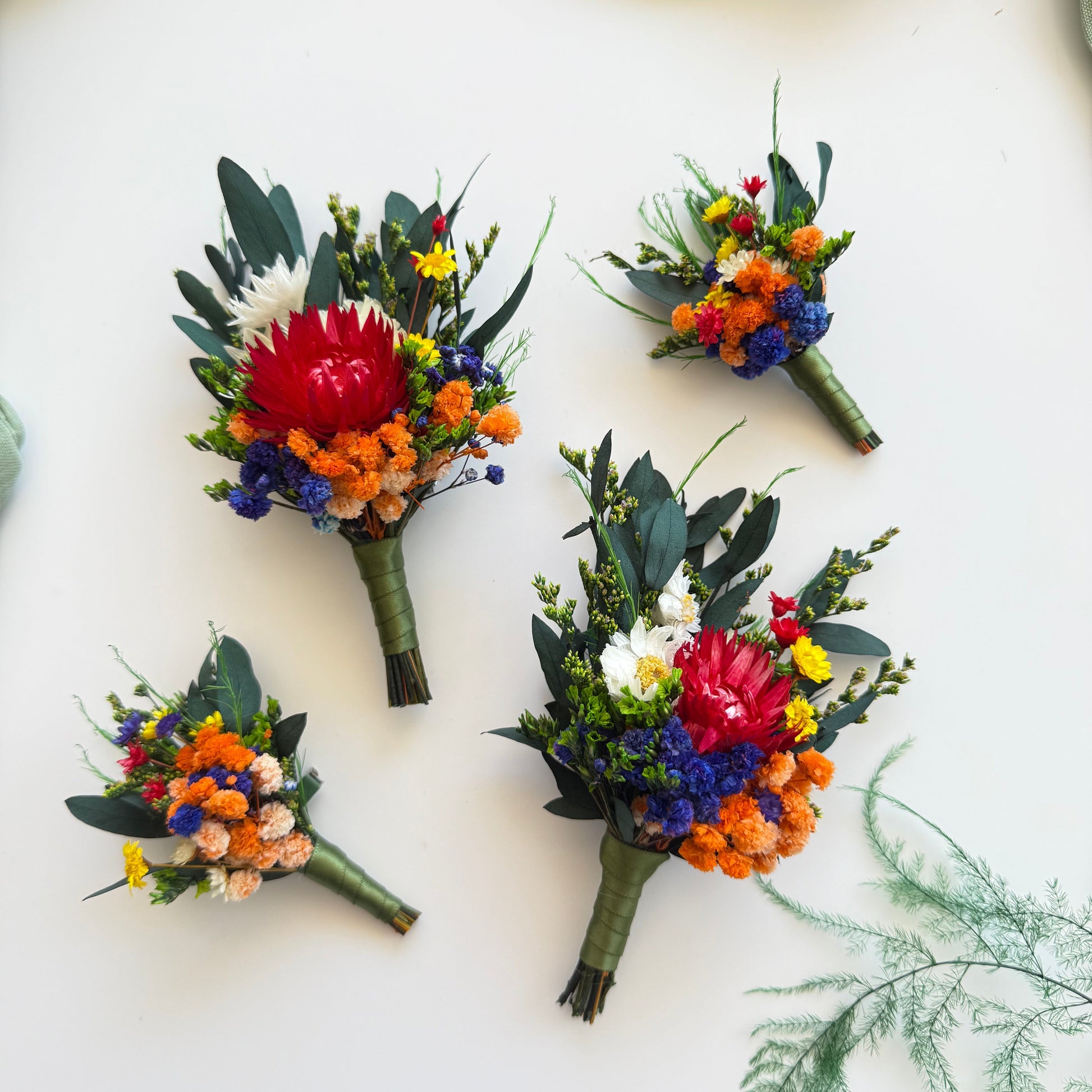 Dried flower wedding boutonniere in rustic boho style with terracotta, blue and sage flowers for groom and groomsmen