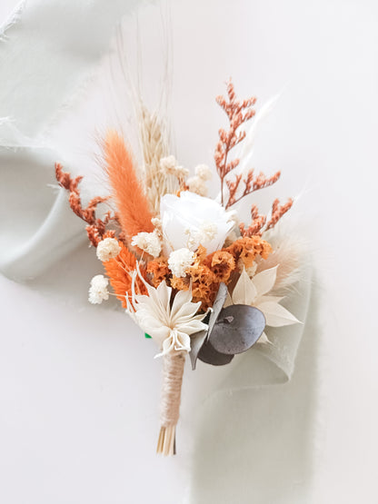 Compact preserved flower arrangement in bright orange and ivory tones, combining sola roses, eucalyptus, bunny tails and wheatgrass.