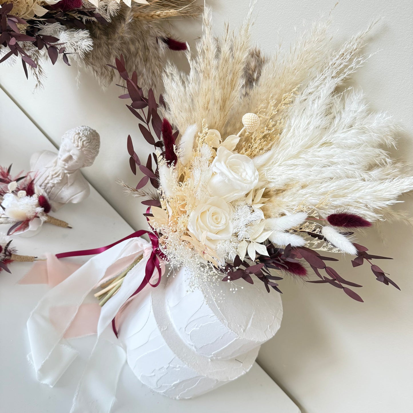 Bouquet of dried flowers with pampas grass and white roses in a white box on a light background